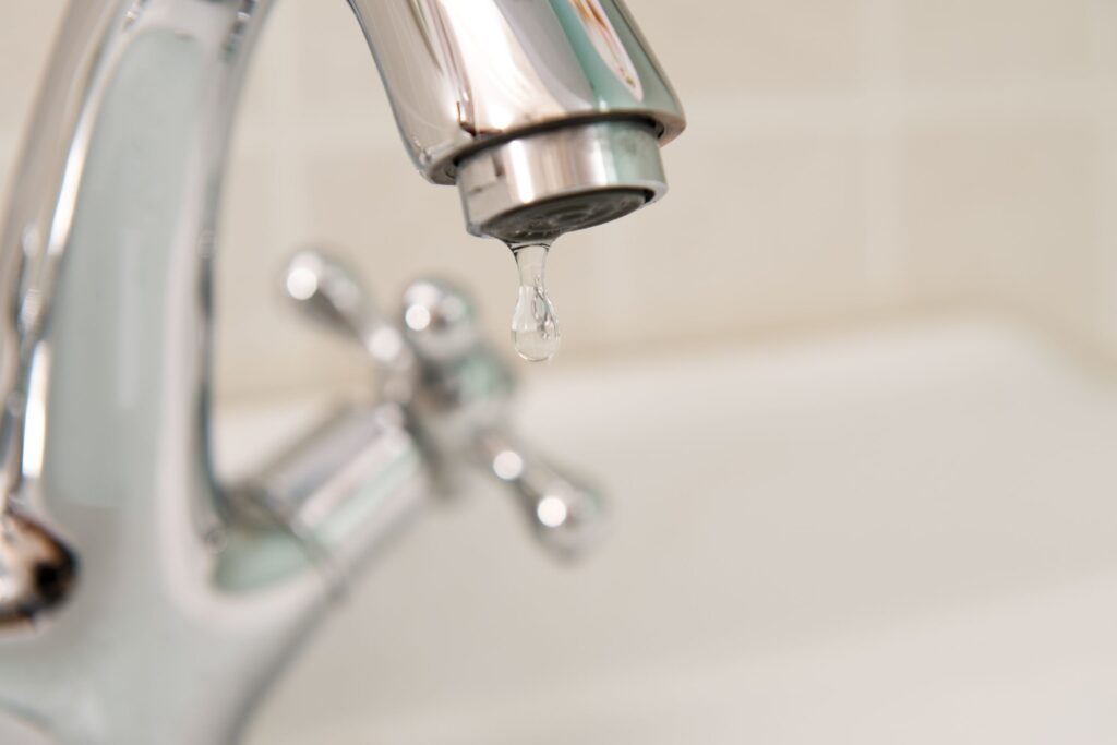 image of bathroom faucet leaking a drop of water