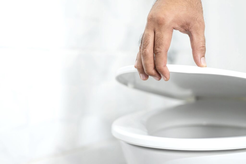 image of a hand lifting up a toilet seat