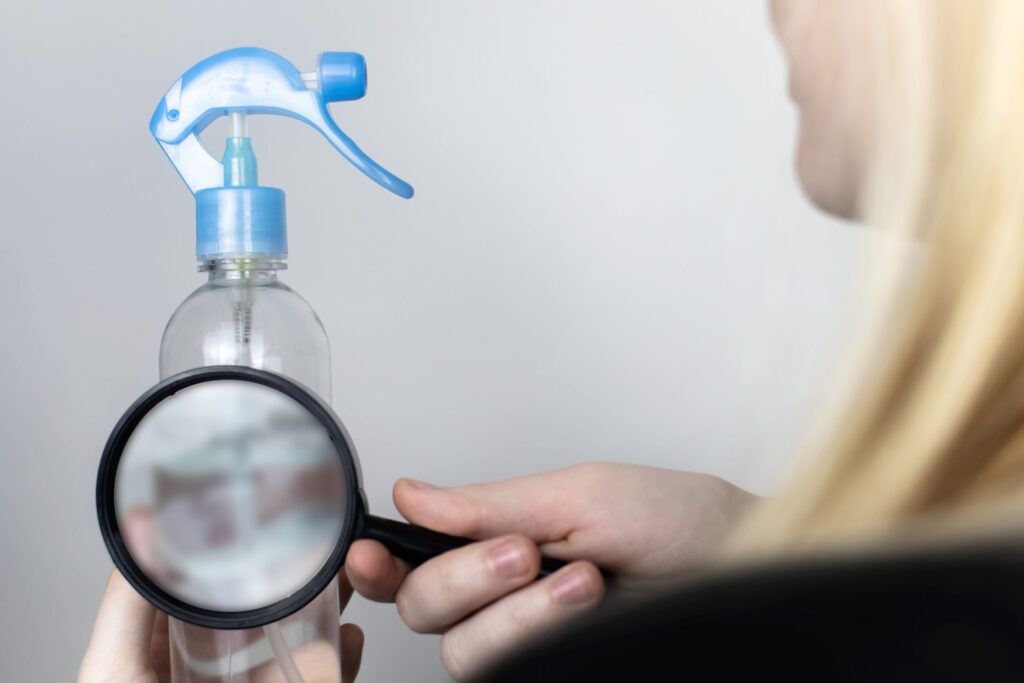 image of a woman looking at a liquid in a bottle through a magnifying glass