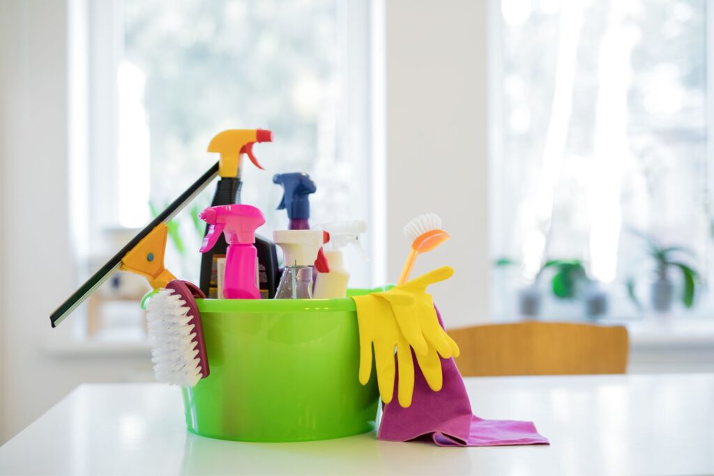 an image of a green bucket full of cleaning supplies on a table