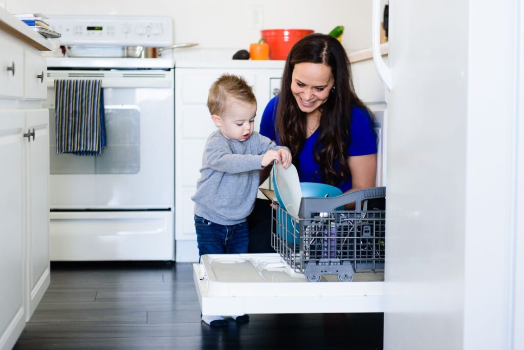 image of mom loading dishwasher with toddler