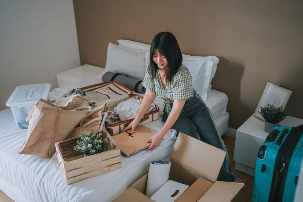 image of a woman decluttering her bedroom by putting everything in boxes on the bed