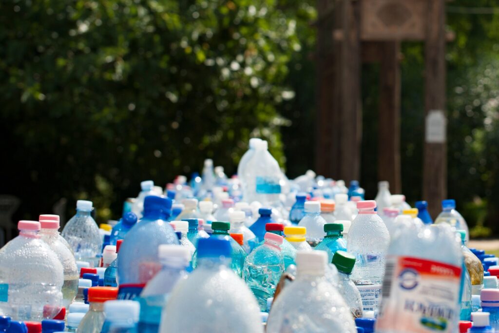 a pile of plastic water bottles in front of some trees