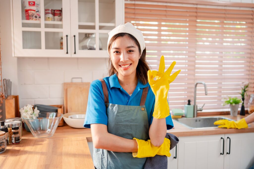 image of a woman in a clean kitchen with yellow gloves making an "okay" sign.