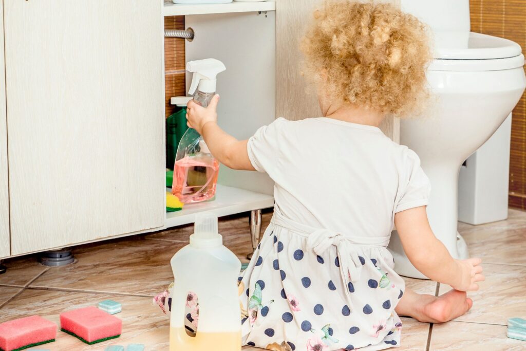 image of a small child taking cleaners out of a bathroom cabinet