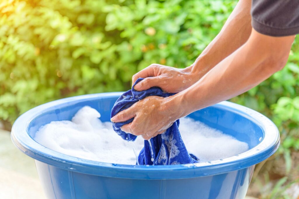 image of someone hand-washing clothes in a tub outside