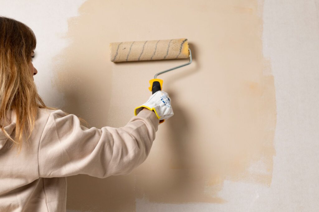 image of a woman painting the wall a light tan