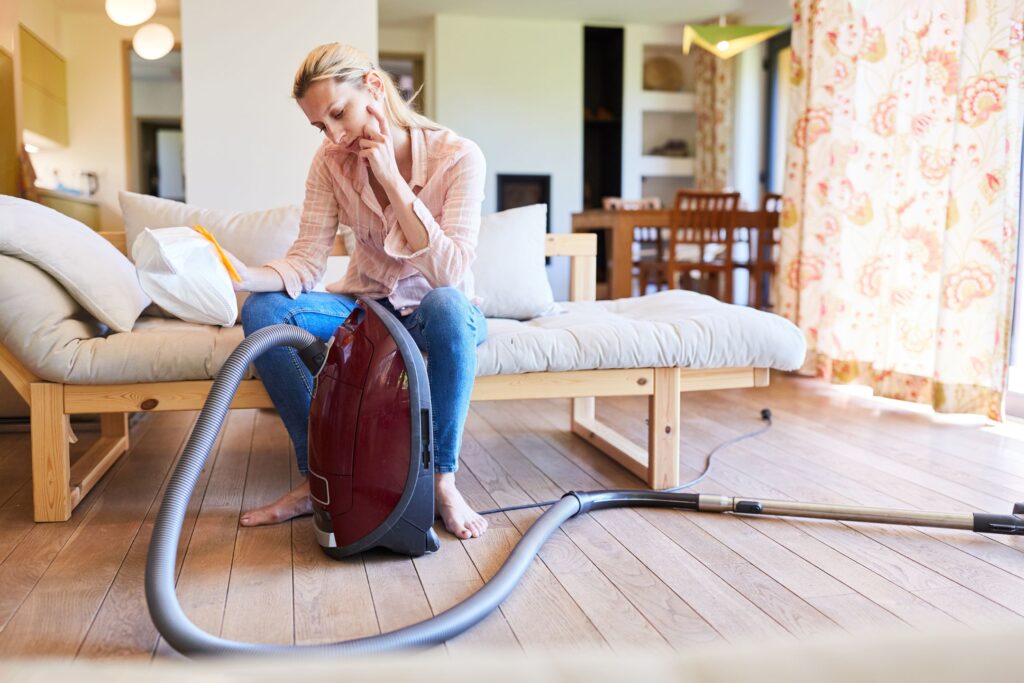 image of a woman sitting on a bed trying to figure out why vacuum isn't working