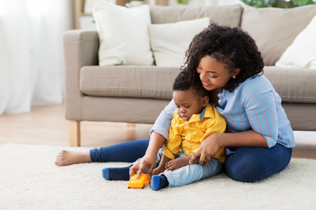 image of a mom and son playing with a car on the carpet