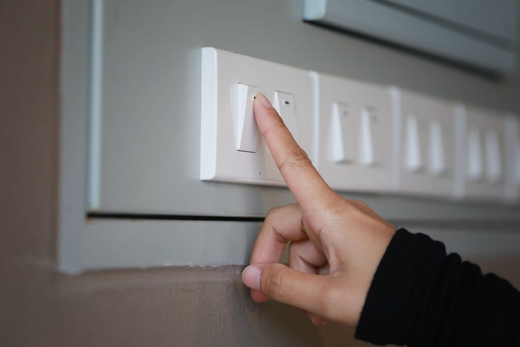 image of a hand in a black sweater turning off the light