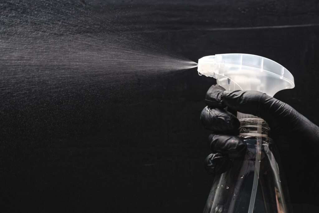 image of a black glove spraying a black solution on a black wall