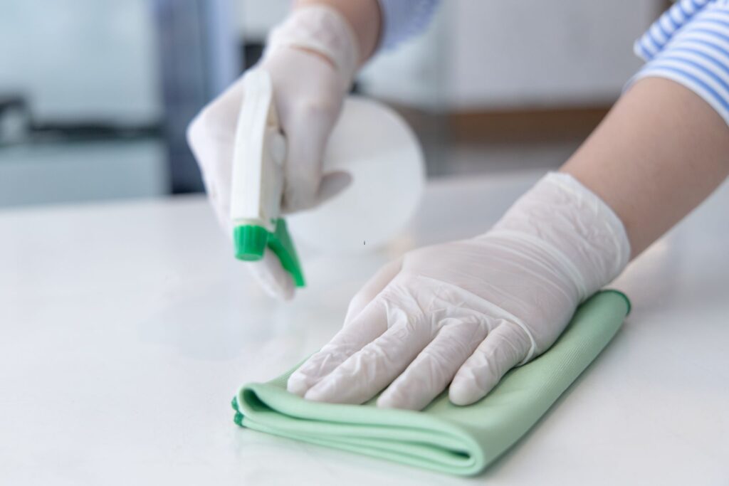 image of a solution being sprayed and a light green cloth cleaning it up