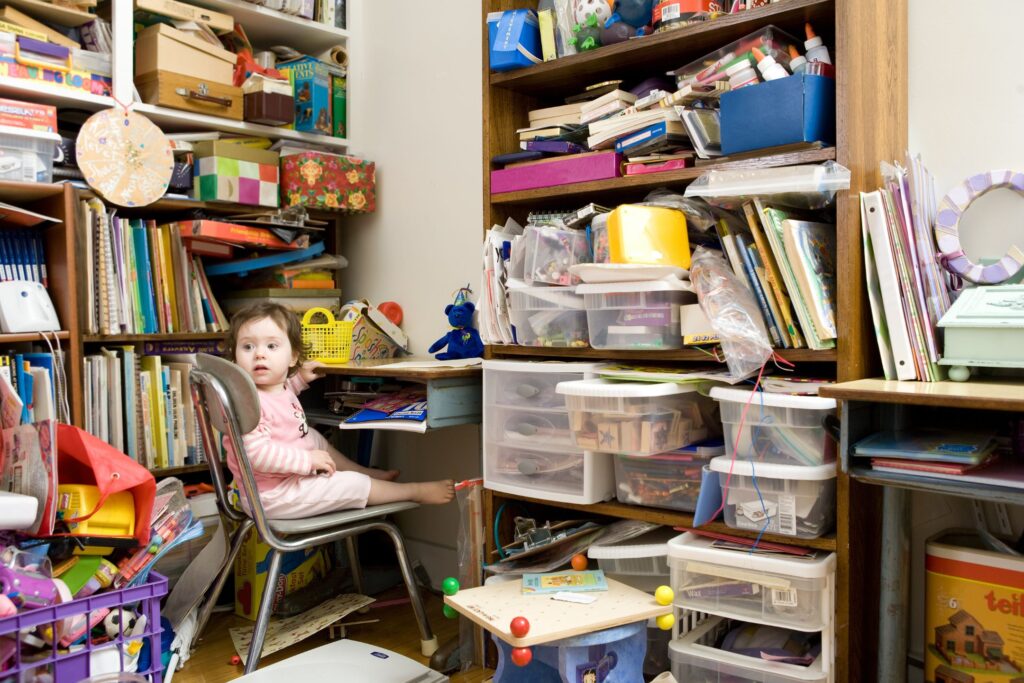 image of a little girl sitting at a desk in a very cluttered room