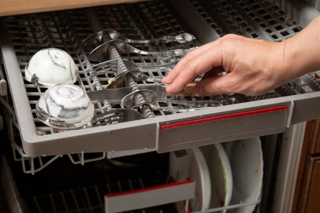 image of a person putting silverware into a dishwasher